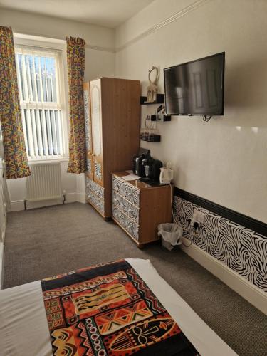a room with a bed and a tv on the wall at Ambassador Guest House in Paignton