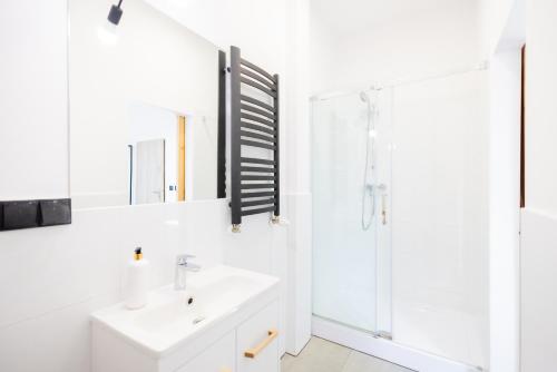 a white bathroom with a sink and a shower at Folwark Matecznik - Spichlerz in Sedzinko