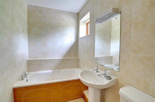 LlanegrynにあるY Bwthynの浴槽と洗面台とバスタブを備えたバスルーム