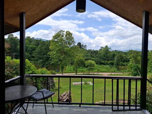 a balcony with a table and chairs and a view of a field at Here in chiang dao in Chiang Dao