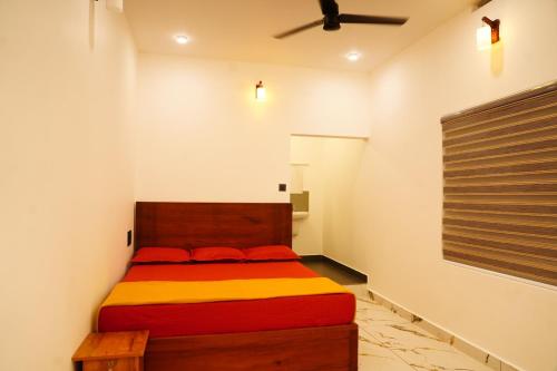 a bedroom with a bed with red and yellow sheets at Sravan Villa in Vagamon
