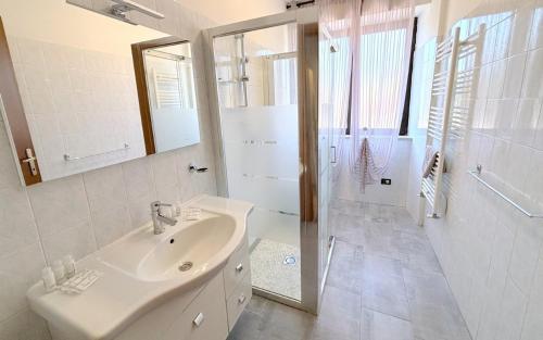 une salle de bains blanche avec un lavabo et un miroir dans l'établissement Fontana Comfort Apartment, à Castelnuovo del Garda