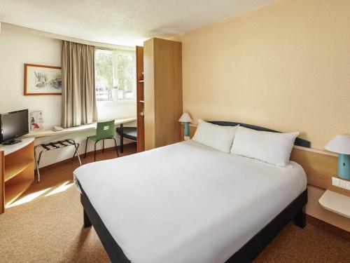 a hotel room with a large bed and a desk at ibis Chartres Ouest Luce in Chartres