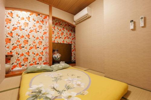 a bedroom with a yellow bed with a flower mural at Just a short walk 心斎橋 Glico Sign 1min 道頓堀30-second 黒門市場 難波駅 Dotonbori Guesthouse 梅の阁 in Osaka