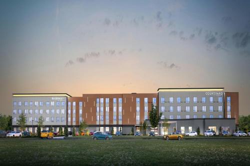 een groot gebouw met auto's geparkeerd in een veld bij Courtyard by Marriott Birmingham Grandview in Birmingham