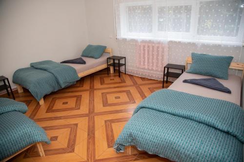 a room with three beds sitting on a wooden floor at Azimut Guest House Self Check-in in Šiauliai