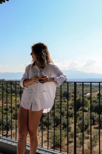 a woman standing on a balcony looking at her cell phone at Puro Dão Hotel & Spa in Nelas