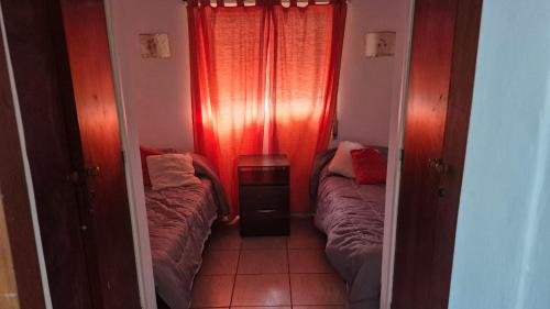 2 camas en una habitación pequeña con cortinas rojas en Don EDELMI 2, en Córdoba