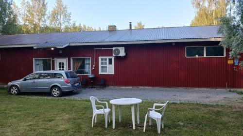 a car parked in front of a red house with a table and chairs at Kaksio oma piha ja autoparkki in Savonlinna