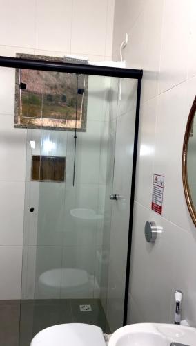a glass shower in a bathroom with a sink at Pousada Catavento in Piraí