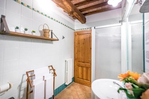 een badkamer met een wastafel en een houten deur bij Casale Il Chicchero in Castel San Gimignano