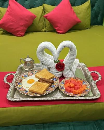 a tray of breakfast food with eggs and fruit on a bed at White Palace airport hotel in Katunayake