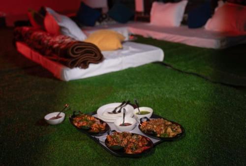 a table with four plates of food on the grass at !!The Valley View Hill-Top Heights & Open Rooftop Cafe !! Bonfire !! Family Hotel Near To Mall Road 100Mtr!! in Vashisht