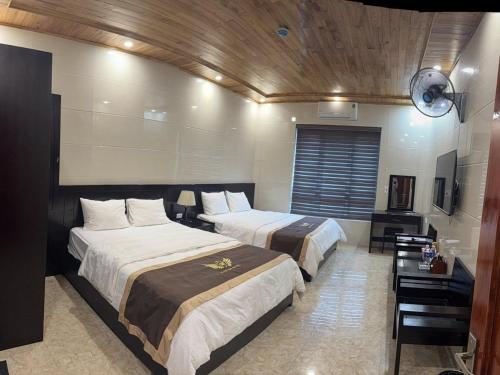 a hotel room with two beds and a television at Khách sạn Giang Sơn Bắc Hà Lào Cai in Bắc Hà