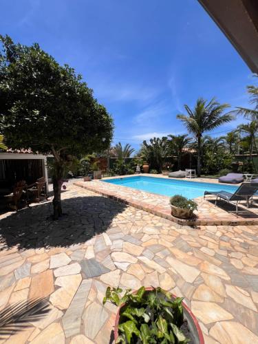 a patio with a pool and a tree and a plant at Vila alecrim Guest House in Búzios
