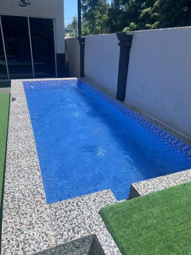 a swimming pool with blue water next to a white wall at POOL CaSSa Ardina pantai Batu hitam 4rooms in Kuantan