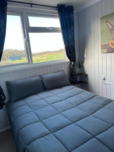 a bed in a bedroom with a large window at The Stables & Silos in Braintree