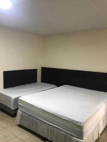 two beds in a room with white sheets at Moradas Araújo in Camboriú