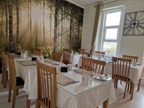 a dining room with tables and chairs and a large window at Ambassador Guest House in Paignton