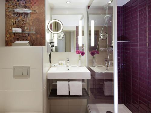 a bathroom with a white sink and purple tiles at Mercure Wien Zentrum in Vienna