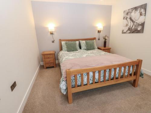 ein Schlafzimmer mit einem Holzbett und zwei Nachttischen in der Unterkunft Cobble Cottage in Long Marton