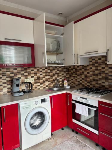 eine Küche mit roten Schränken und einer Waschmaschine in der Unterkunft Apartament chirie la zi in Chişinău