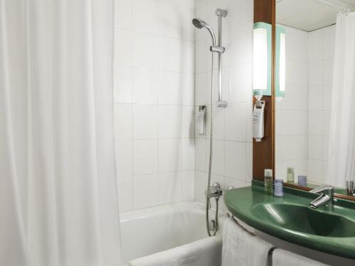 y baño con lavabo verde y bañera. en ibis Douala, en Douala