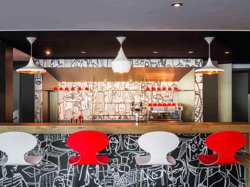 a bar with red chairs and a black and white wall at ibis Nantes Centre Gare Sud in Nantes