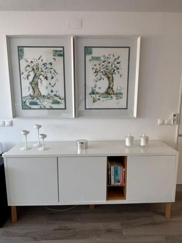 a white cabinet with two pictures on the wall at The luxury suite in Alicante