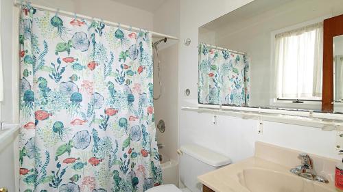 une salle de bain avec un rideau de douche et des toilettes dans l'établissement Renascence Cottage, à Cape May Point