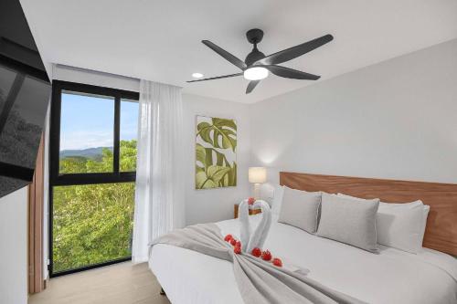 Schlafzimmer mit einem Bett, einem Deckenventilator und einem Fenster in der Unterkunft Heavenly View - 2 BDRM Oceanview Apartment in Jacó