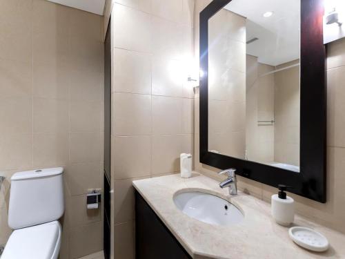a bathroom with a sink and a toilet and a mirror at Furnished Studio In The Pearl - FGR2 in Doha