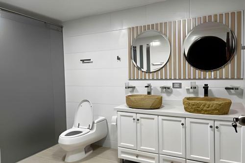 a bathroom with a toilet and two sinks and a mirror at Apt Palos Altos Poblado, a distancia caminando de restaurantes in Medellín