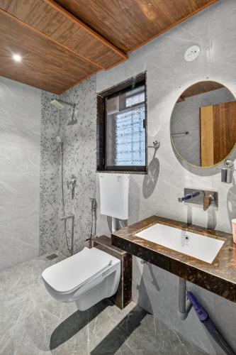 a bathroom with a toilet and a sink and a mirror at Koko House - Infinity pool in Panchgani
