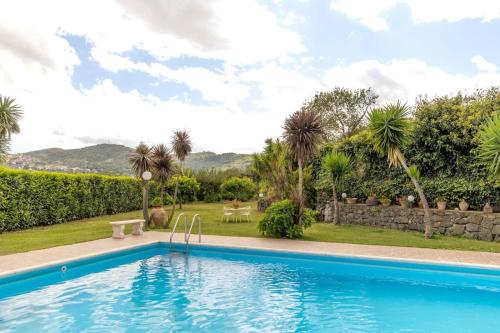 een zwembad in een tuin met palmbomen bij Villa Jelù in Castiglione di Sicilia