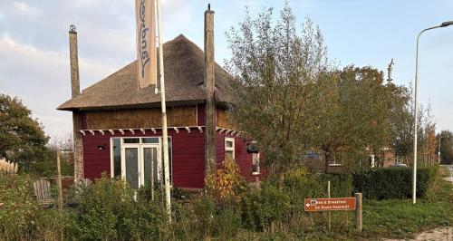 a small red building with a sign in front of it at De Rooie Hooimijt in Ammerzoden
