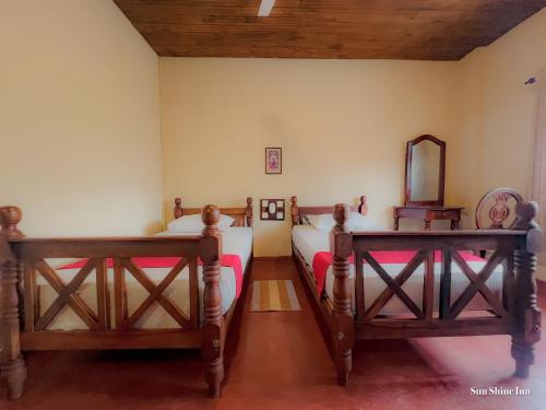two twin beds in a room with a mirror at Sun Shine Inn Unawatuna in Galle