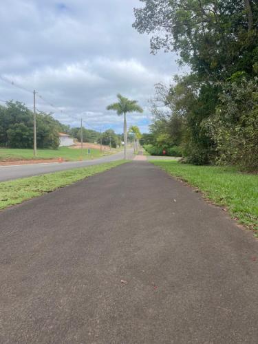 an empty road with two palm trees in the distance at Recanto dos Sonhos Ninho Verde 2 in Pardinho