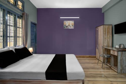 een slaapkamer met een groot bed met paarse muren bij Hotel O Junaki Inn in Guwahati