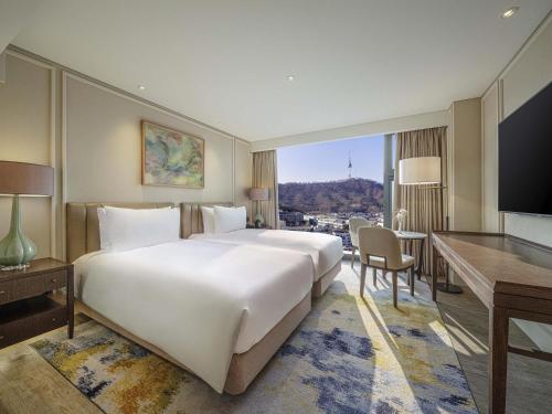 a bedroom with a large white bed and a desk at The Ambassador Seoul - A Pullman Hotel in Seoul