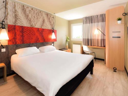 a bedroom with a large white bed in a hotel at ibis Beaune La Ferme Aux Vins in Beaune