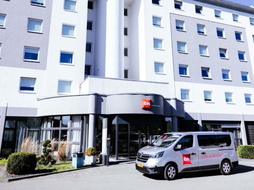 a white van parked in front of a building at Ibis Luxembourg Airport in Luxembourg