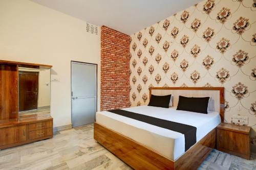 Un dormitorio con una cama y una pared de ladrillo. en SPOT ON Ksg Bakery, en Mandor