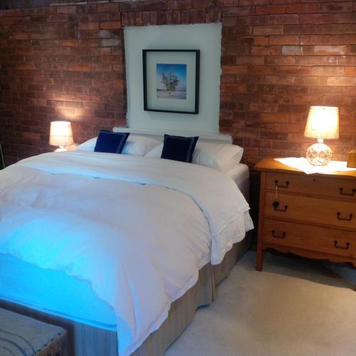 a bedroom with a large white bed and a brick wall at Picturesque School House Retreat in Meaford