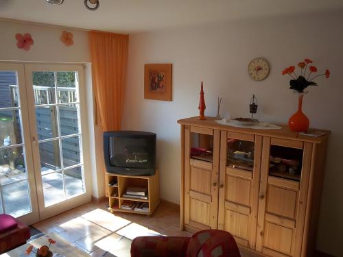 - un salon avec une télévision et une armoire dans l'établissement Ferienhaus Barbara am Meer, à Horumersiel