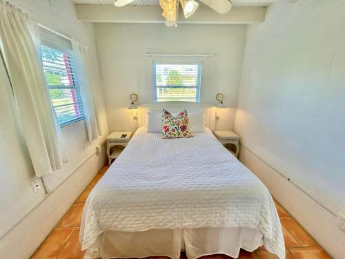 een slaapkamer met een wit bed en 2 ramen bij Baked Beach Bungalow in St. George Island