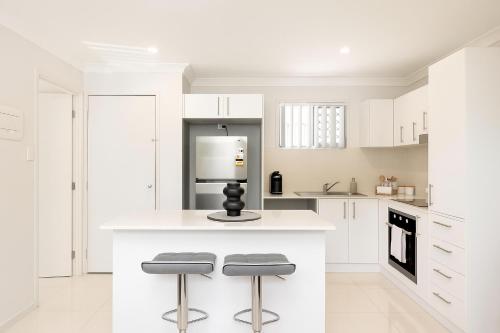 a kitchen with white cabinets and a counter with stools at Smart Suites Self Check-in Apartments - S Freney in Brisbane