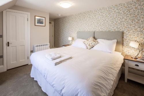 a bedroom with a large white bed with two towels on it at La Croix Guest House in Isle of Jersey