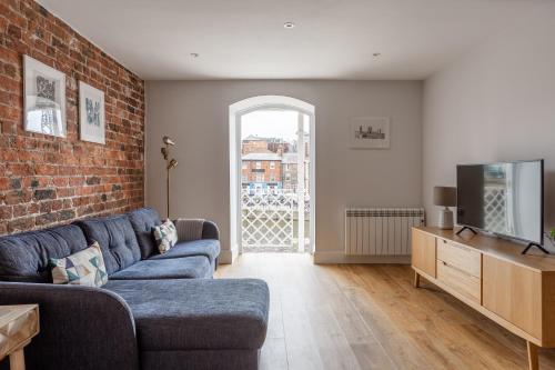 een woonkamer met een blauwe bank en een bakstenen muur bij Luxury Apartment Woodsmill View - on the river - with balcony - Recently refurbished in York
