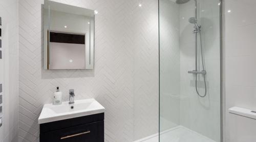 een witte badkamer met een wastafel en een douche bij Luxury Apartment Woodsmill View - on the river - with balcony - Recently refurbished in York